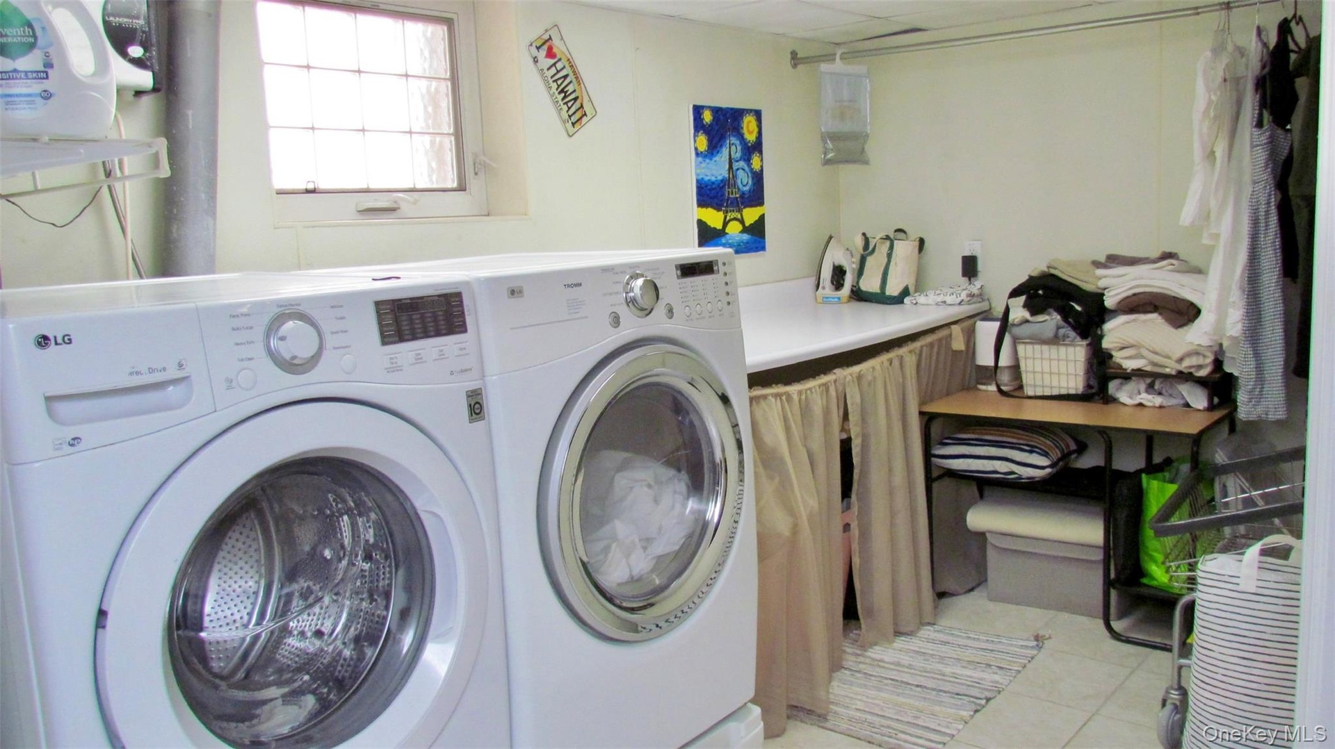 Laundry area featuring a window, built-in countertop, tile flooring, and overhead lighting