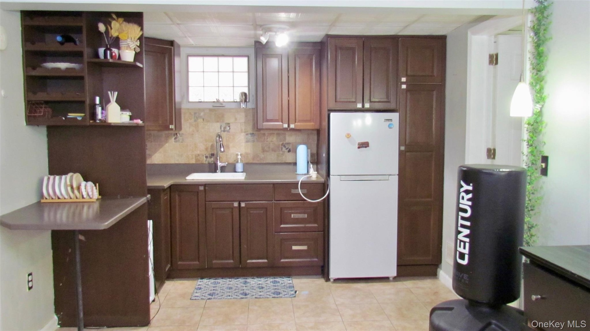 Wood-finish cabinetry, a white basin sink, and a tiled backsplash