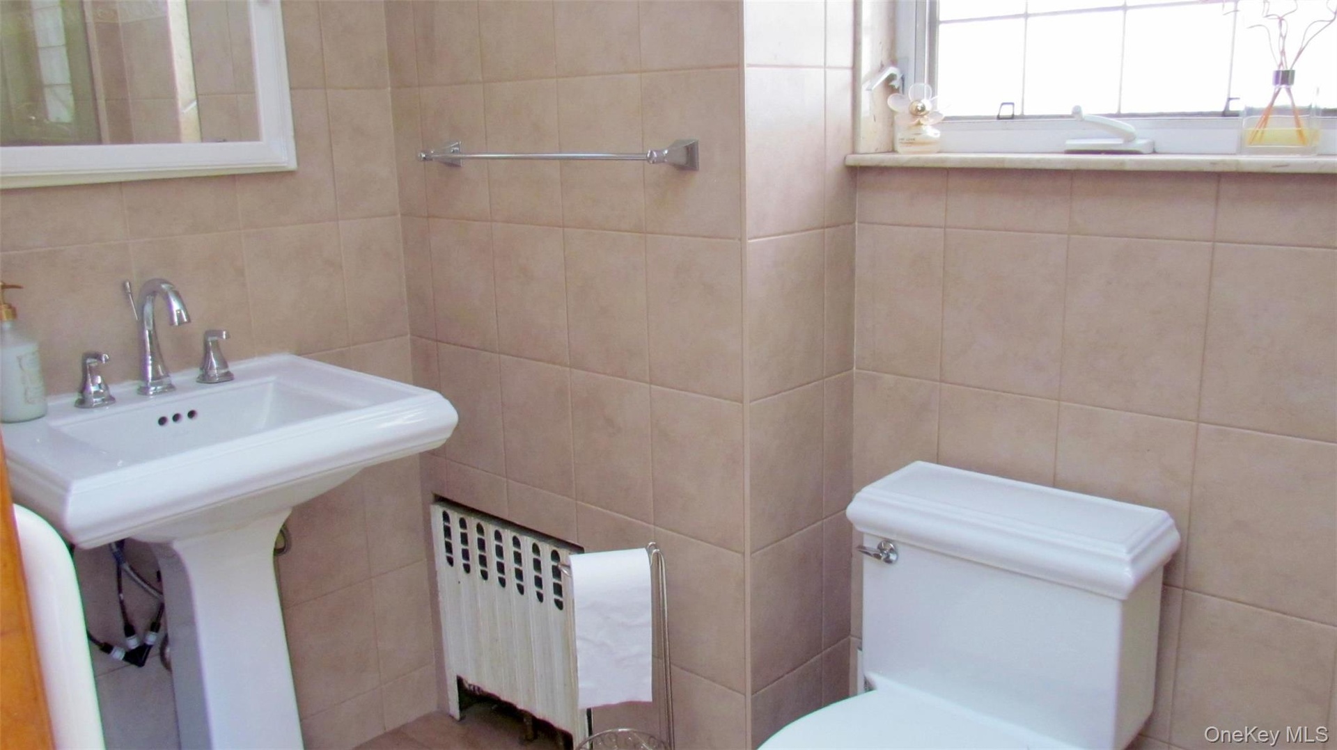Pedestal sink with chrome faucet set, tiled walls, and leaded glass window