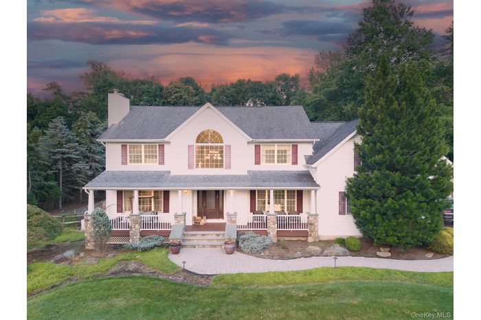 Classic Colonial-style residence featuring a symmetrical white exterior, arched transom windows, and a welcoming front porch with railings