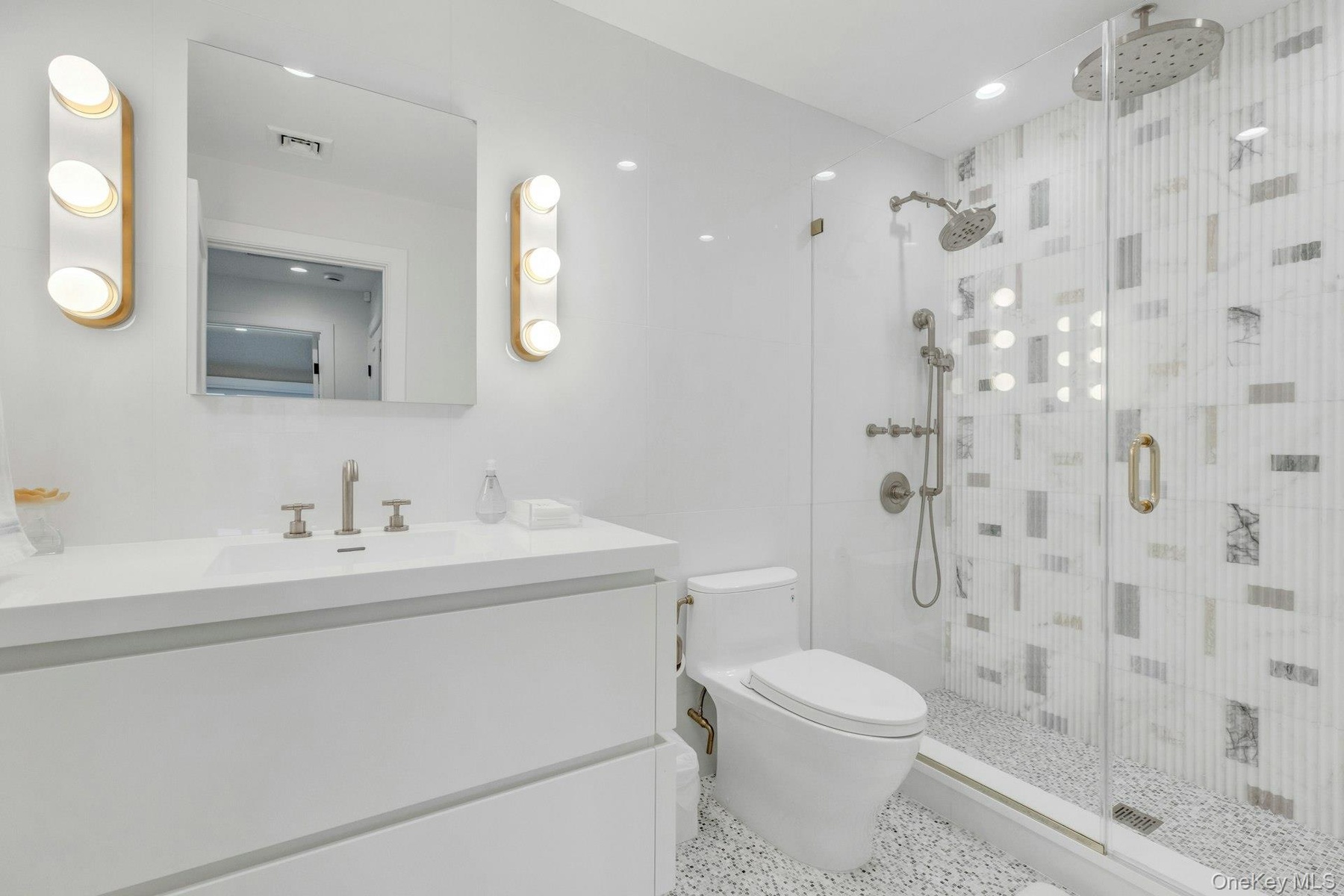 Modern bathroom featuring a glass-enclosed shower with dual shower heads, mosaic tile shower surround, and pebble-finish floor