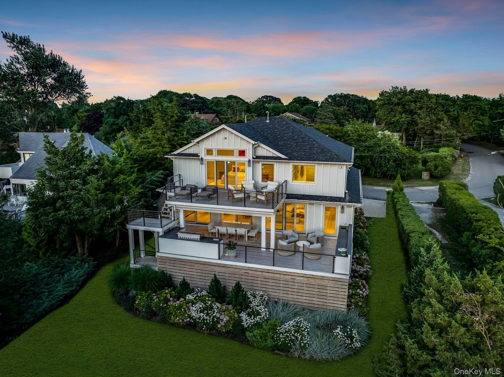 Modern multilevel residence with multiple outdoor decks, a manicured lawn, and mature landscaping