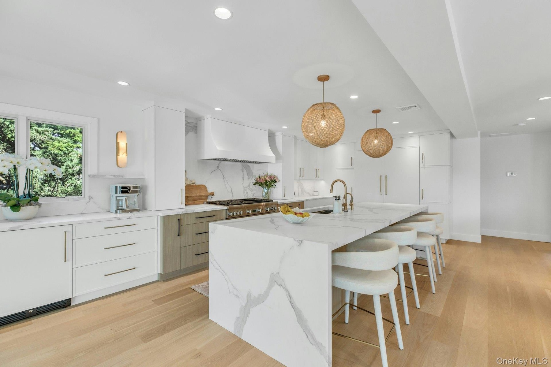 Gourmet kitchen featuring a waterfall island with integrated seating, professional-grade range, full-height cabinetry, wood-finish flooring, and reces