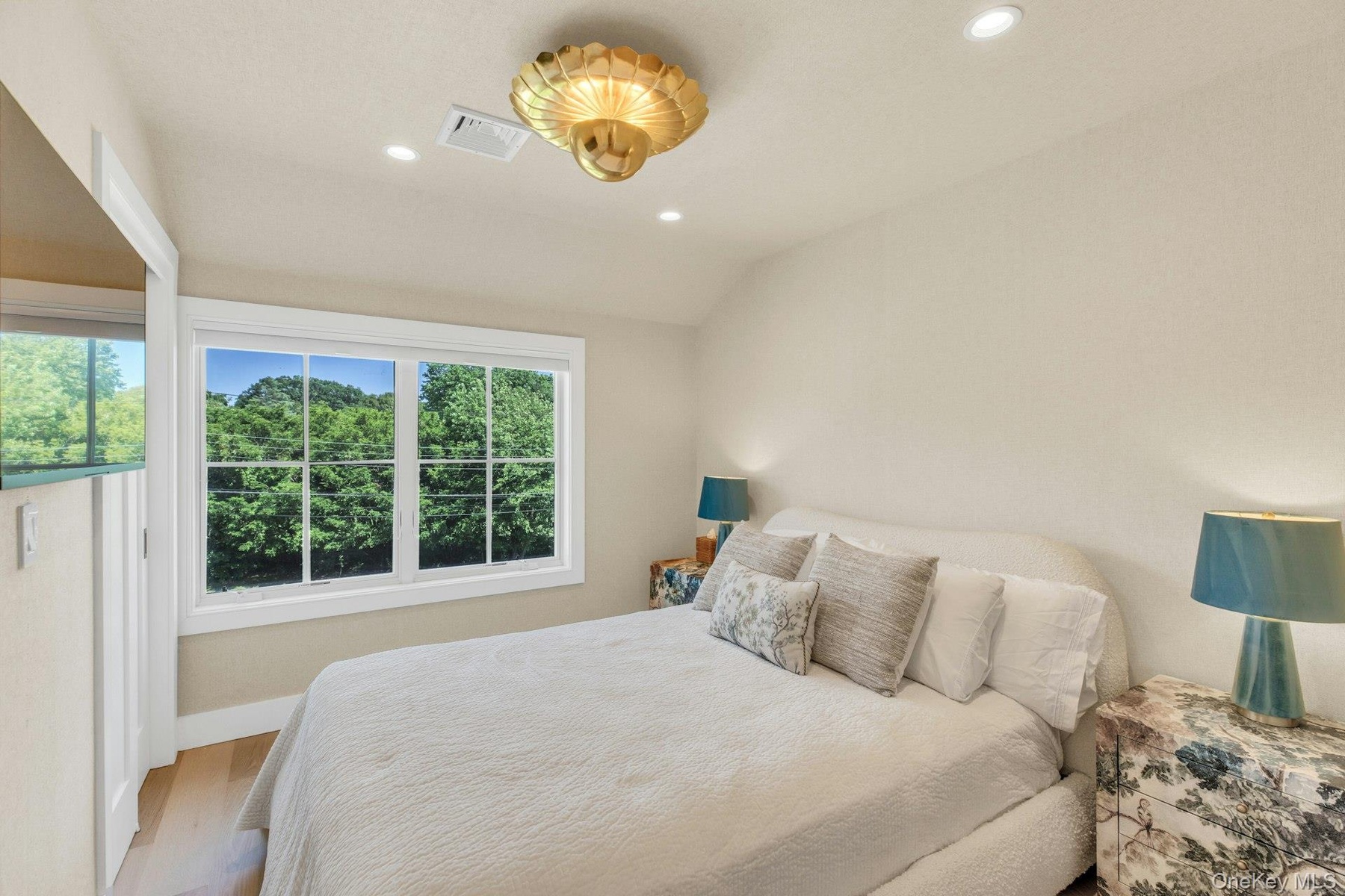 Spacious room featuring a multi-pane window with white trim, wood-finish flooring, a textured wall finish, recessed lighting, and a decorative gold-to