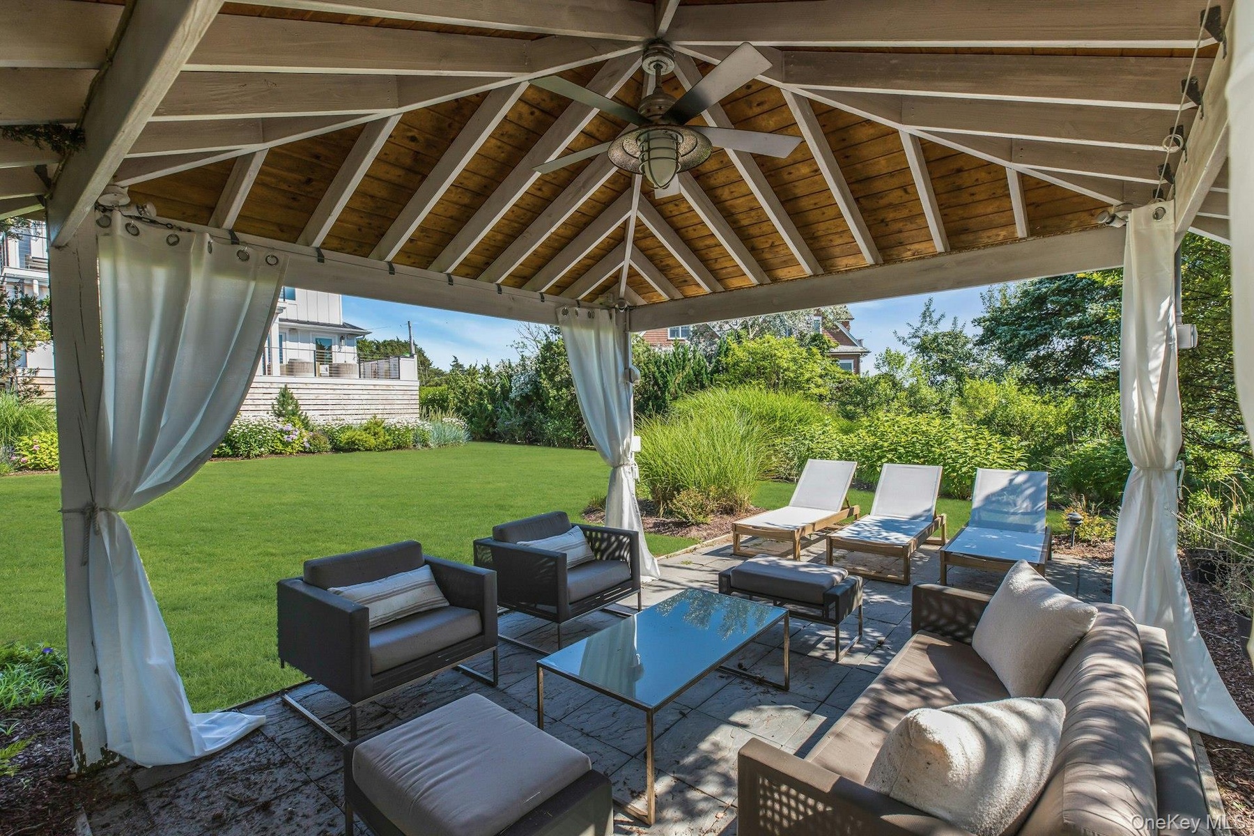 Covered patio featuring a wood-finish ceiling, central ceiling fan, and privacy drapes
