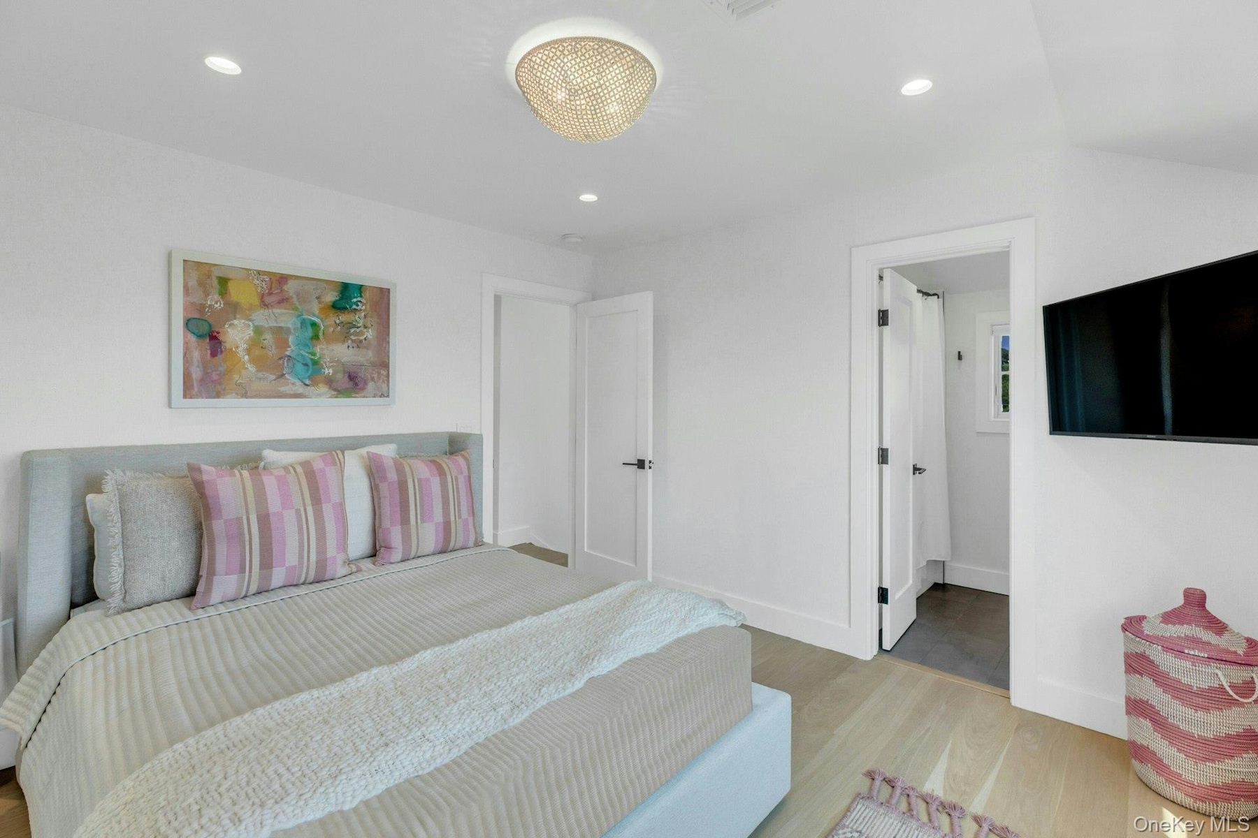 Guest Bedroom with Light wood-finish flooring complements white walls with recessed lighting and a central decorative fixture