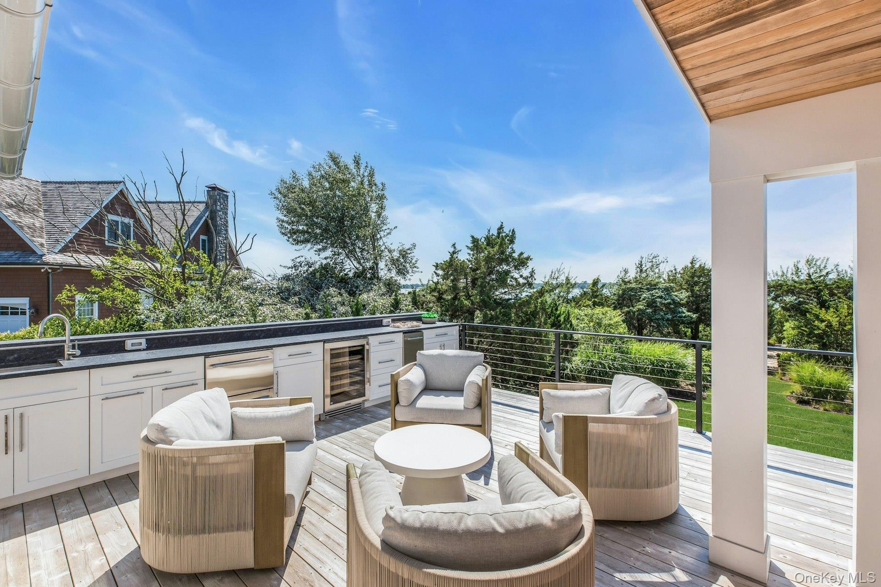 Expansive outdoor deck featuring wood-finish decking and a built-in outdoor kitchen with a sink, integrated grill, and beverage refrigerator