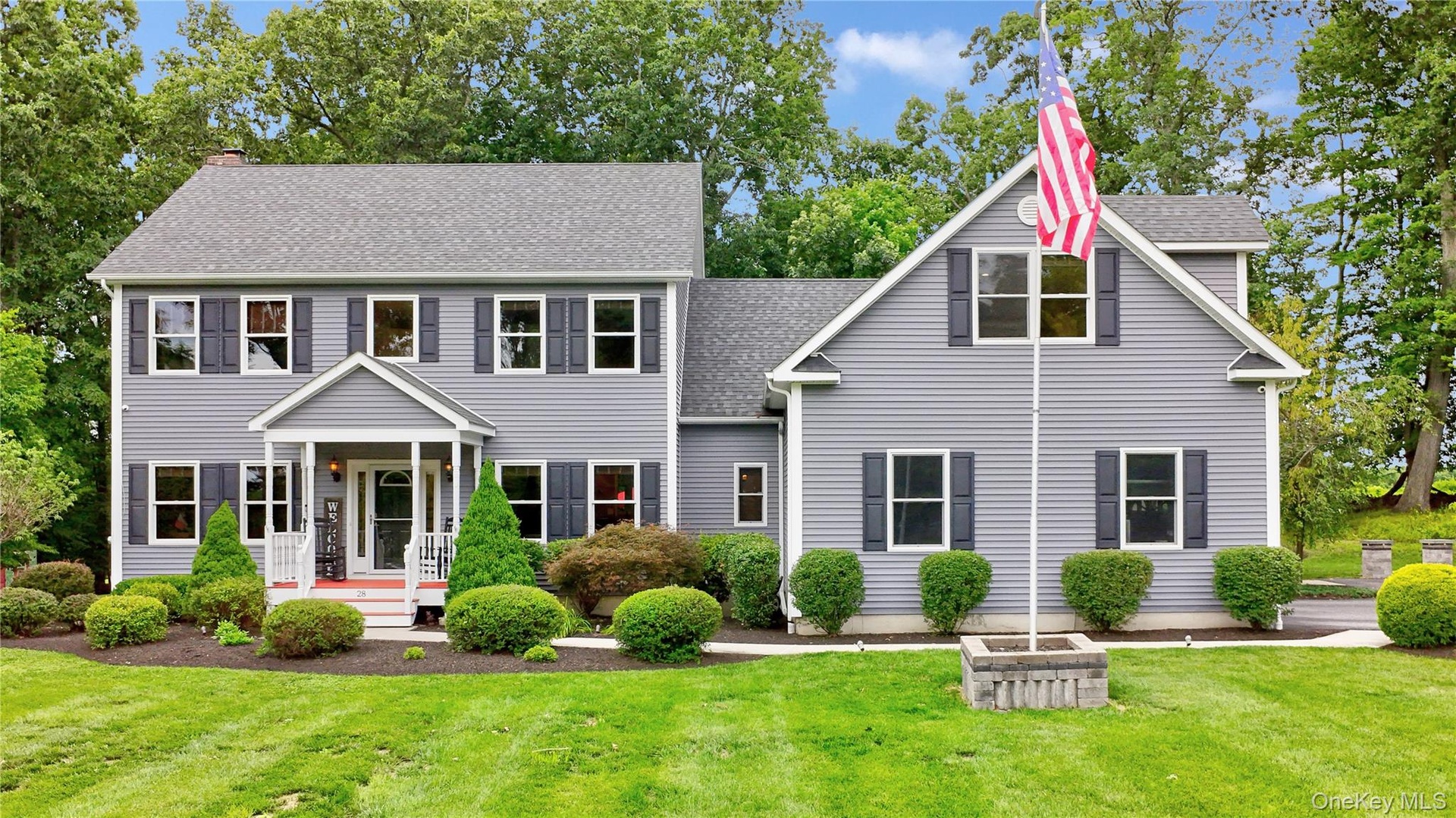 Two-story residence with legal accessory apartment featuring light gray siding, dark shutters, and a covered front porch with white railings