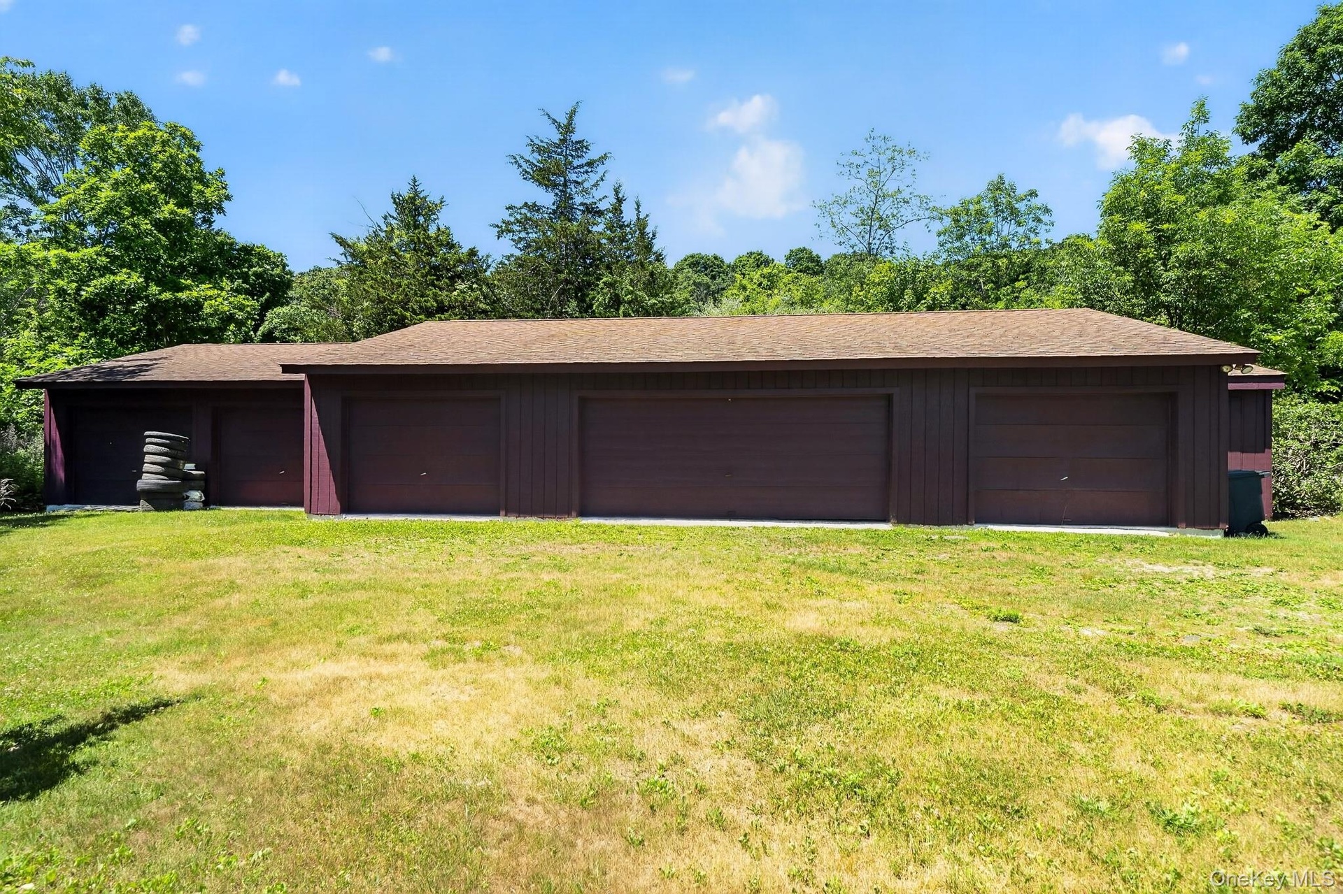 Multi-bay garage structure featuring multiple brown garage doors and a brown shingle roof
