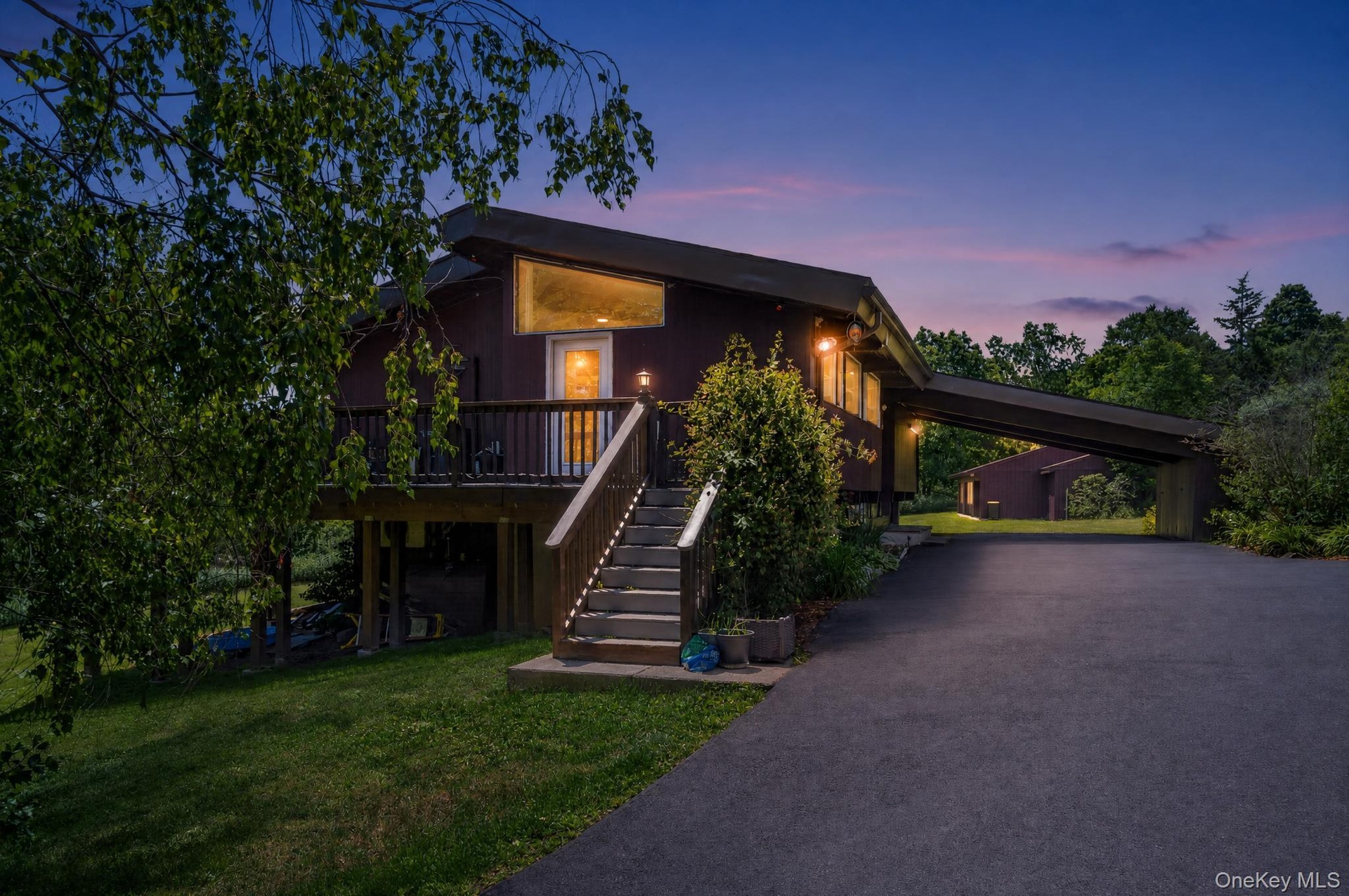 Contemporary-style residence featuring a dark exterior, elevated deck, and prominent exterior staircase