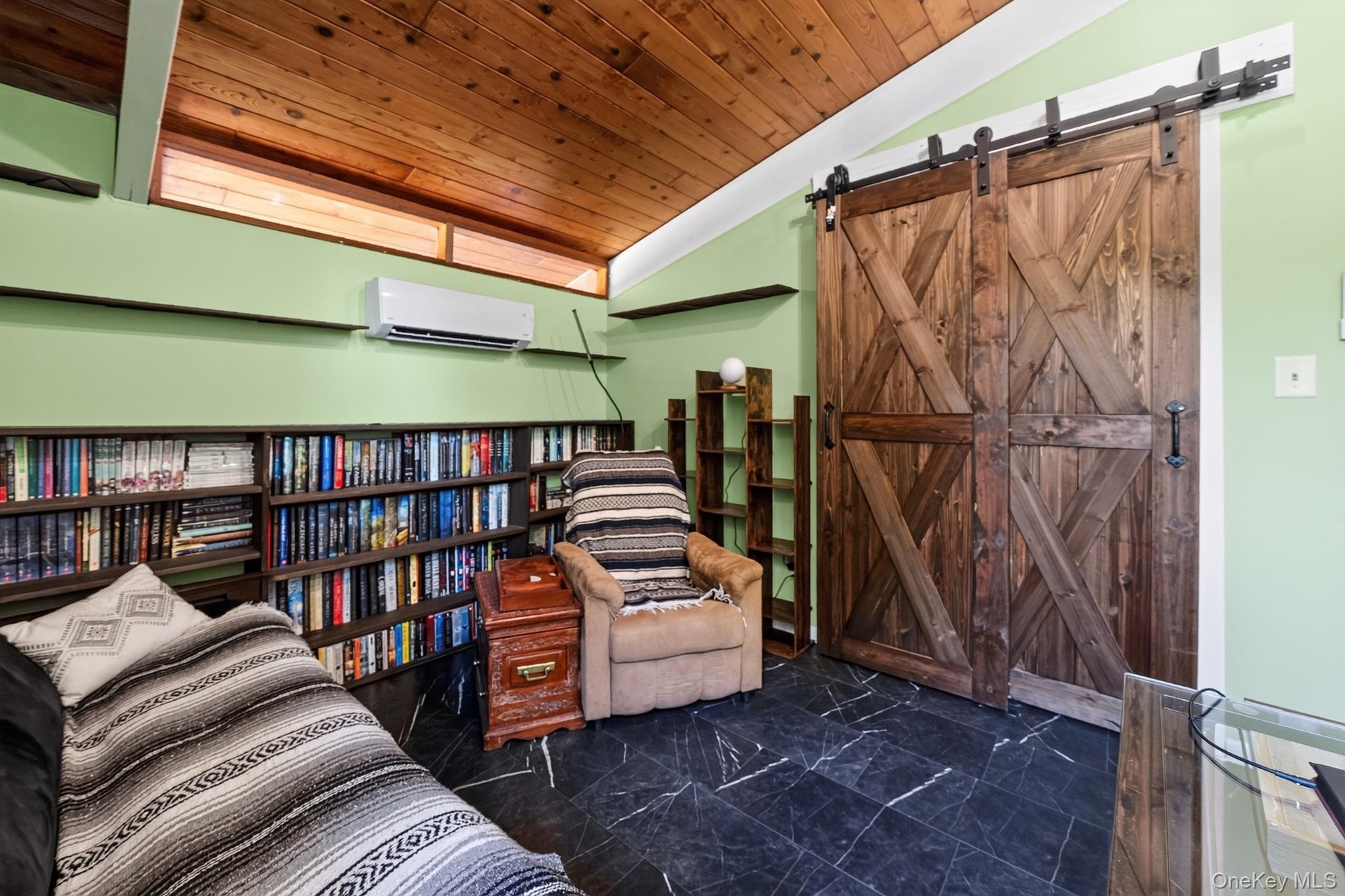 Interior space featuring a sloped wood-finish ceiling, black tile flooring, and custom wood barn doors with black metal hardware