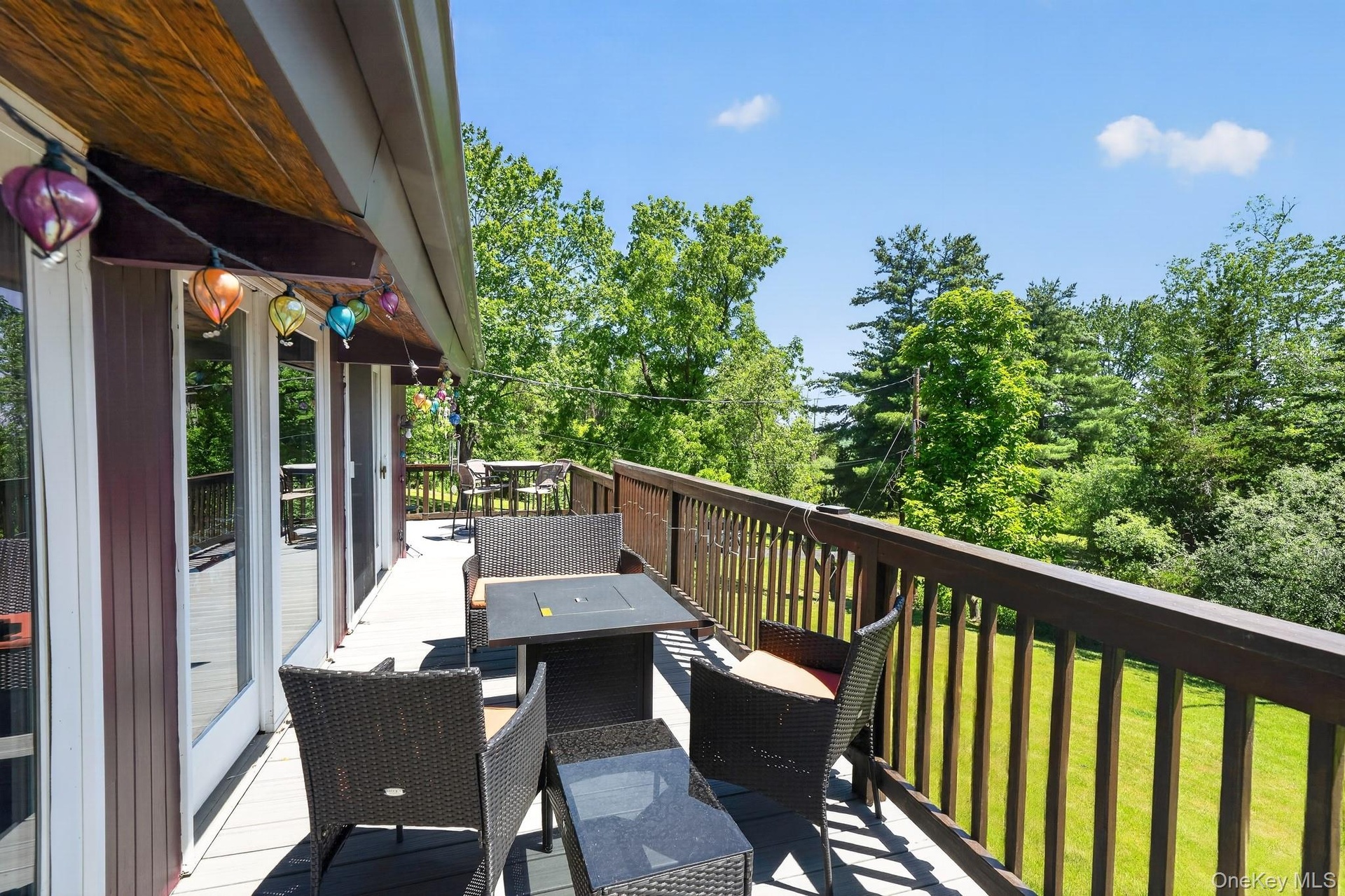 Expansive outdoor deck featuring wood-finish railing, composite decking, and multiple glass-paneled doors