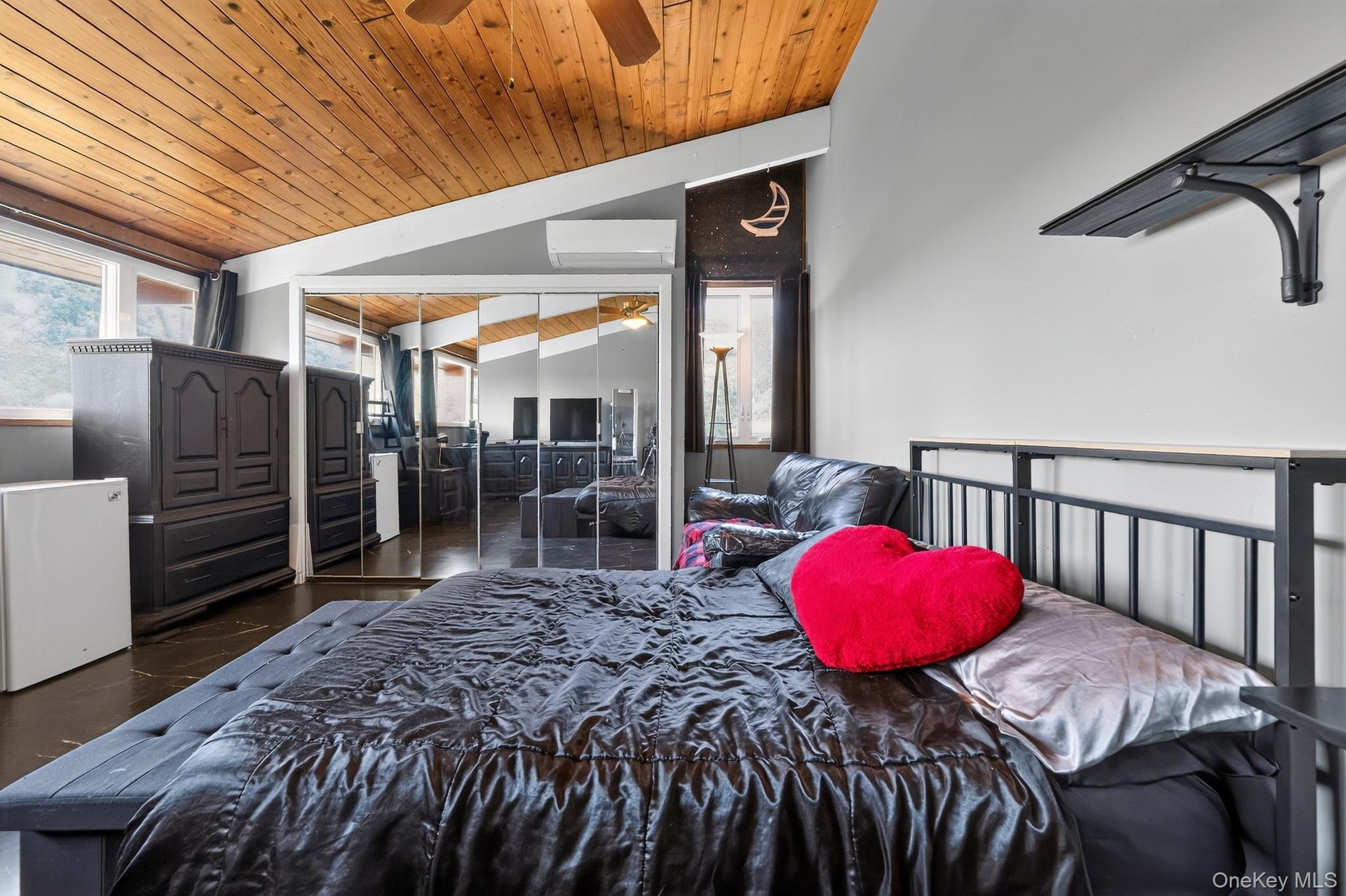 Vaulted wood-paneled ceiling with a ceiling fan, mirrored closet doors, dual windows, and built-in shelving