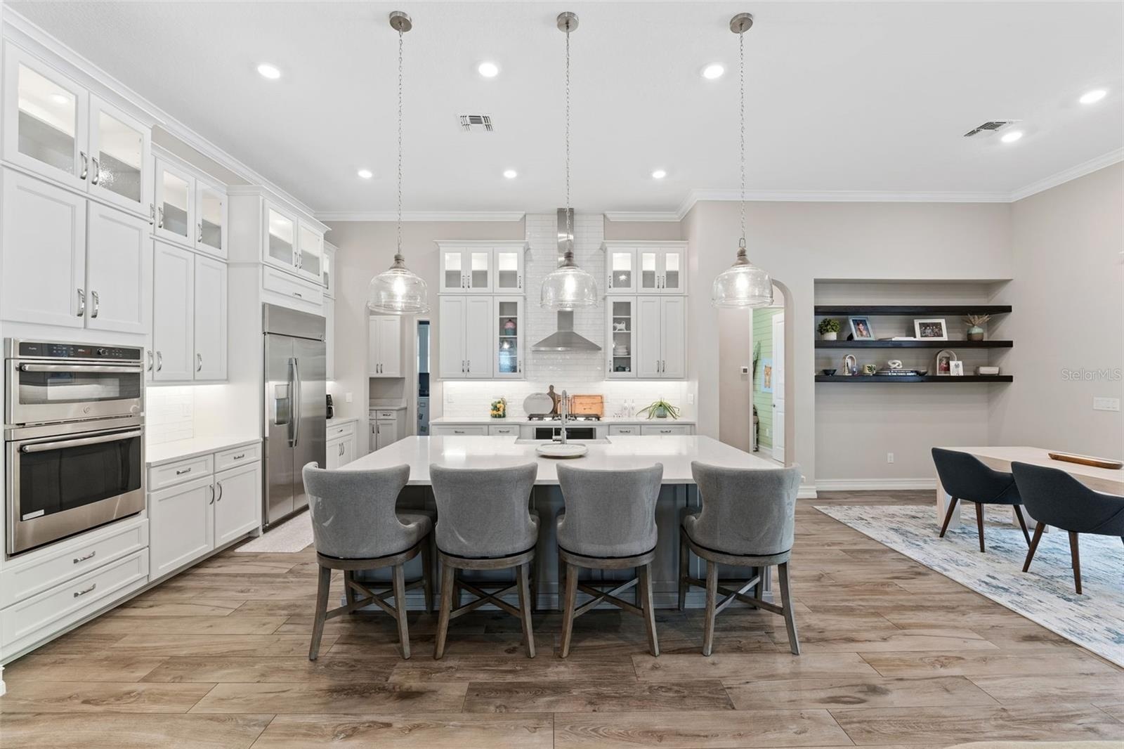 Spacious and open gourmet kitchen features built-in oven, cooktop with hood, quartz countertops, built-in lighting and more.
