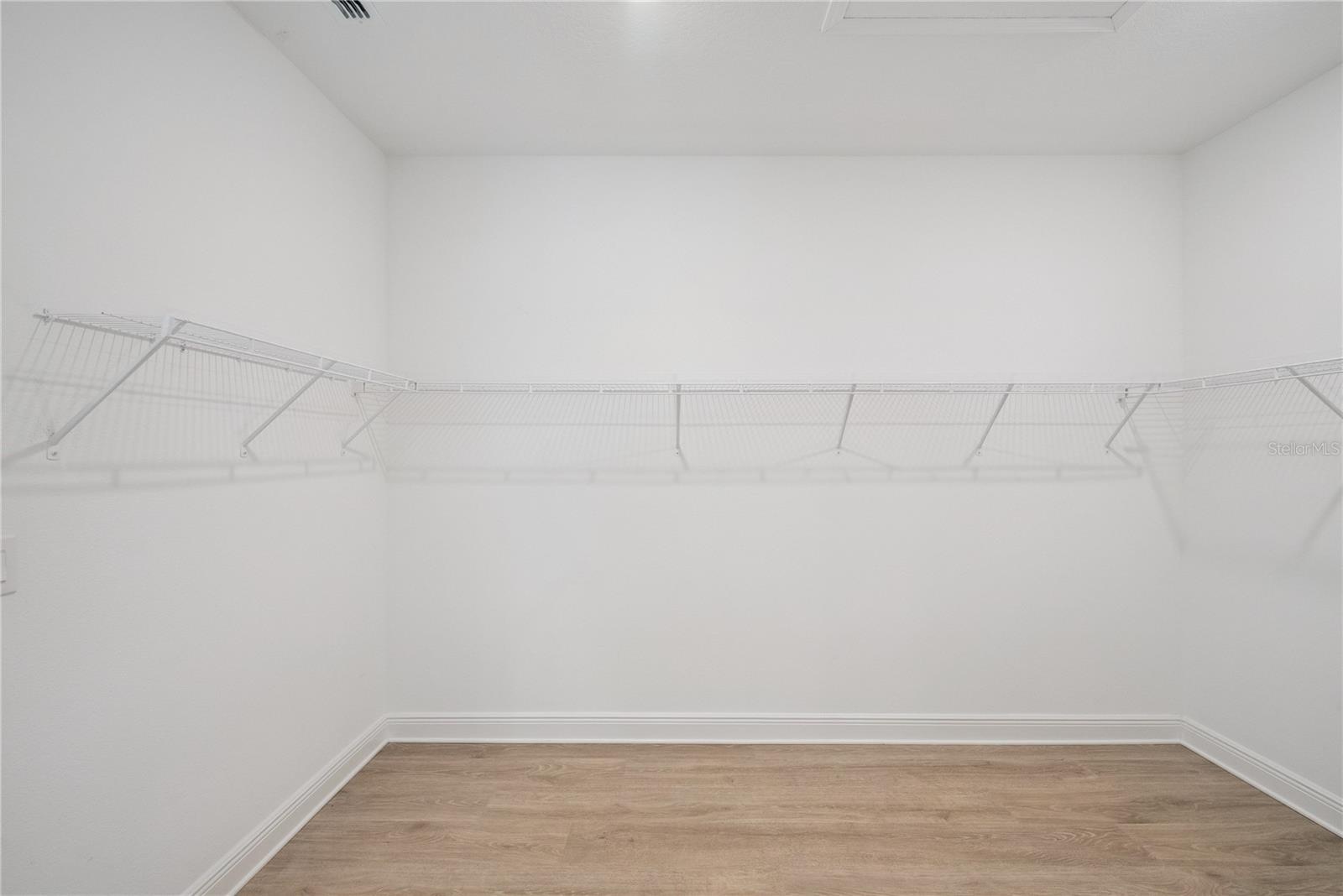Primary bedroom closet that connects to laundry room.