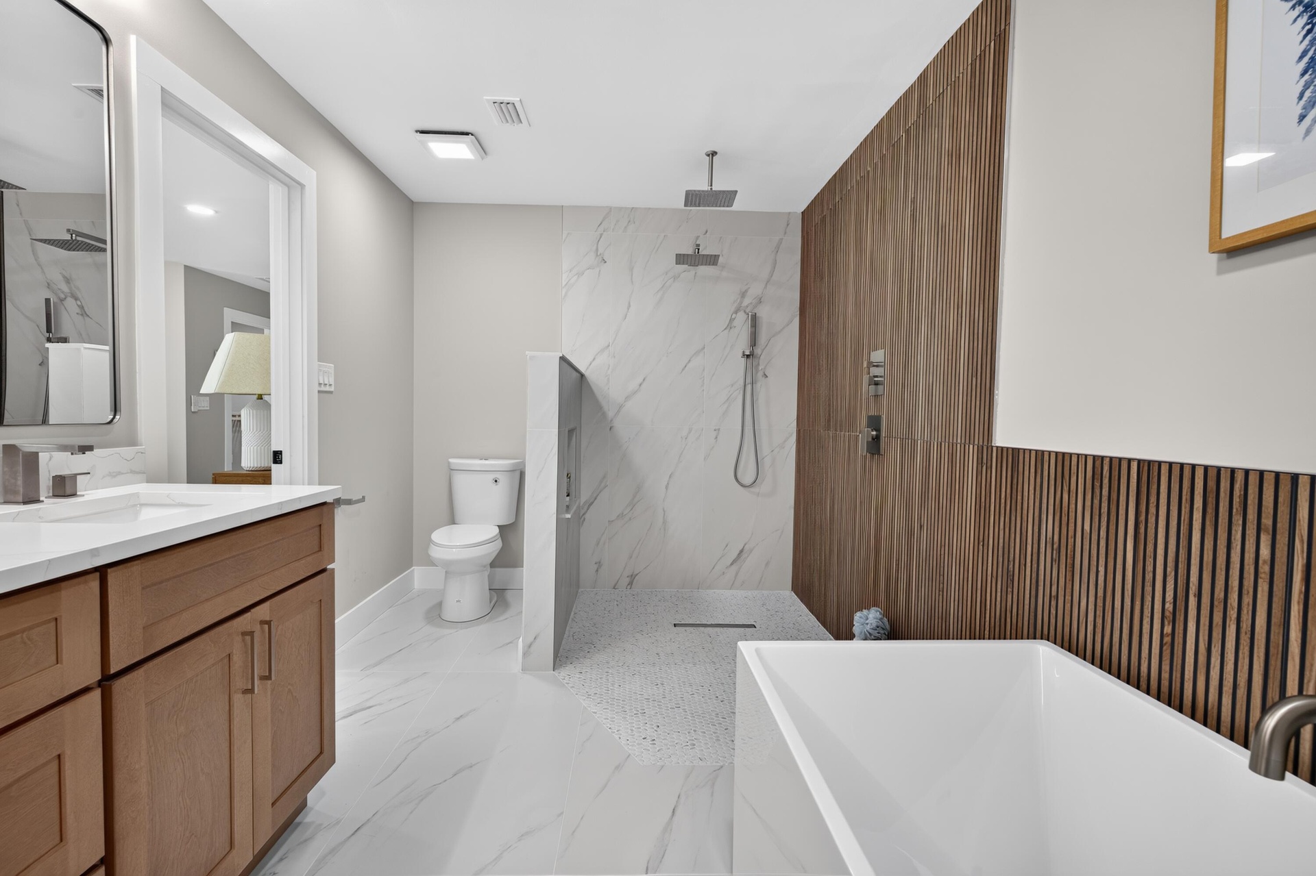 Contemporary bathroom featuring a freestanding soaking tub, wood-finish accent wall, and a walk-in shower with a rainfall showerhead