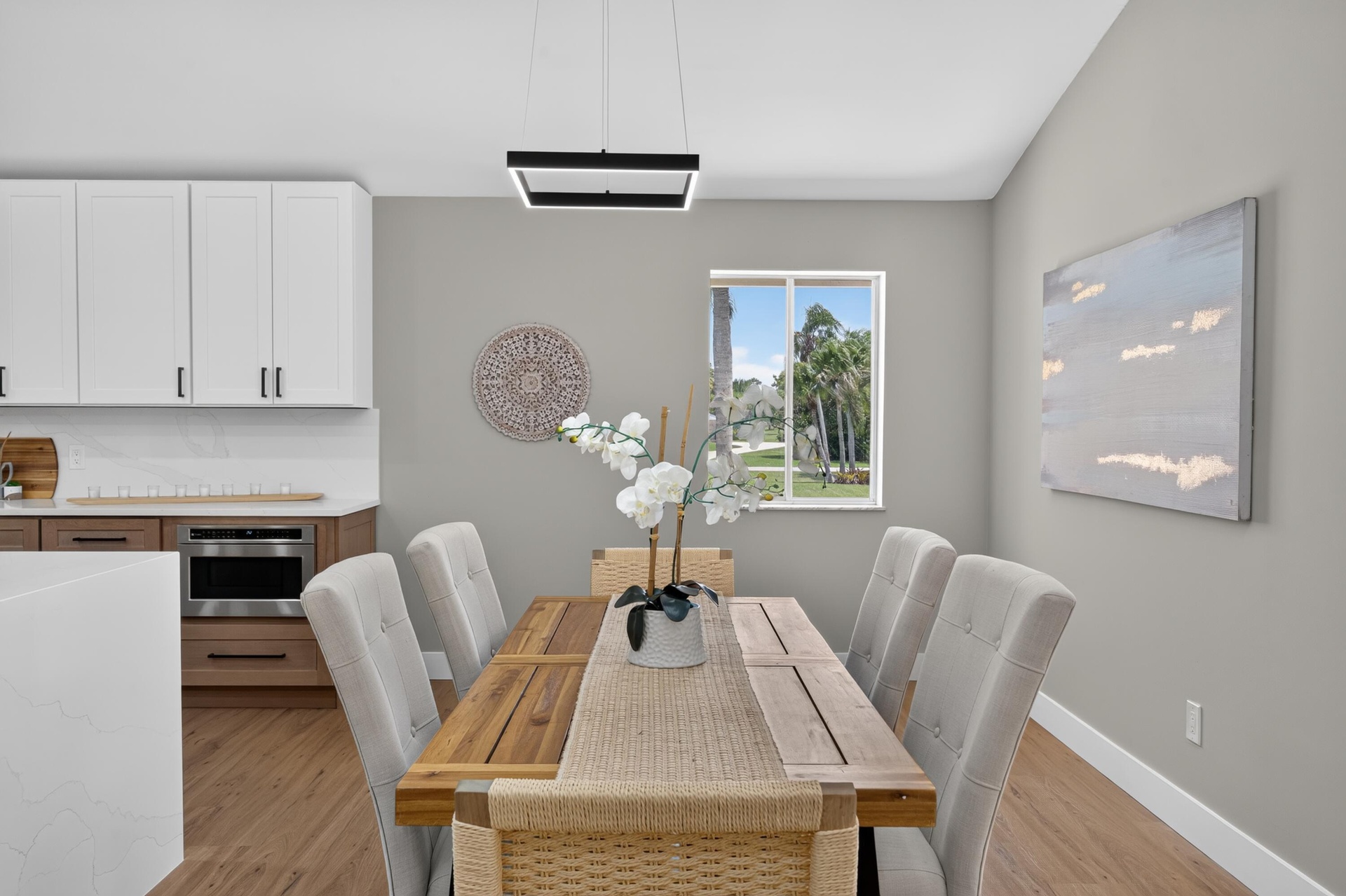 Dining area featuring wood-finish flooring, a contemporary linear chandelier, and a window providing natural light