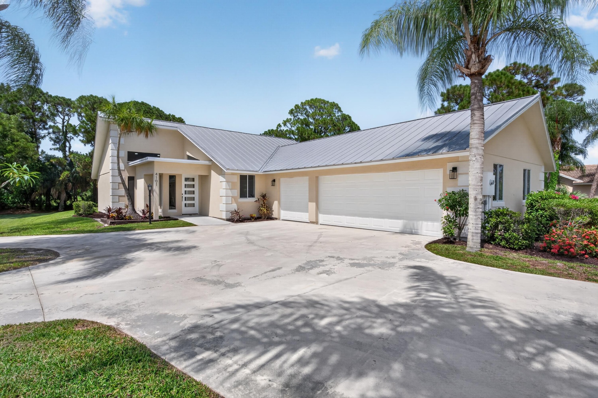Contemporary stucco exterior with a metal roof and an expansive concrete driveway