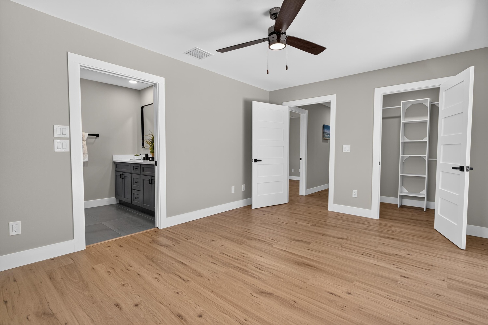 Spacious room featuring wood-finish flooring, light gray walls, and a contemporary ceiling fan