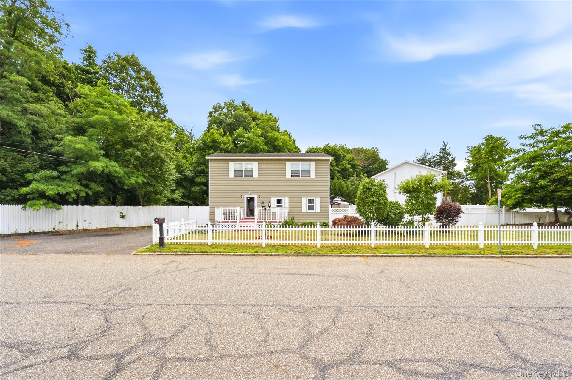 Corner Property Two-story residence featuring a neutral exterior, white trim, and a white picket fence