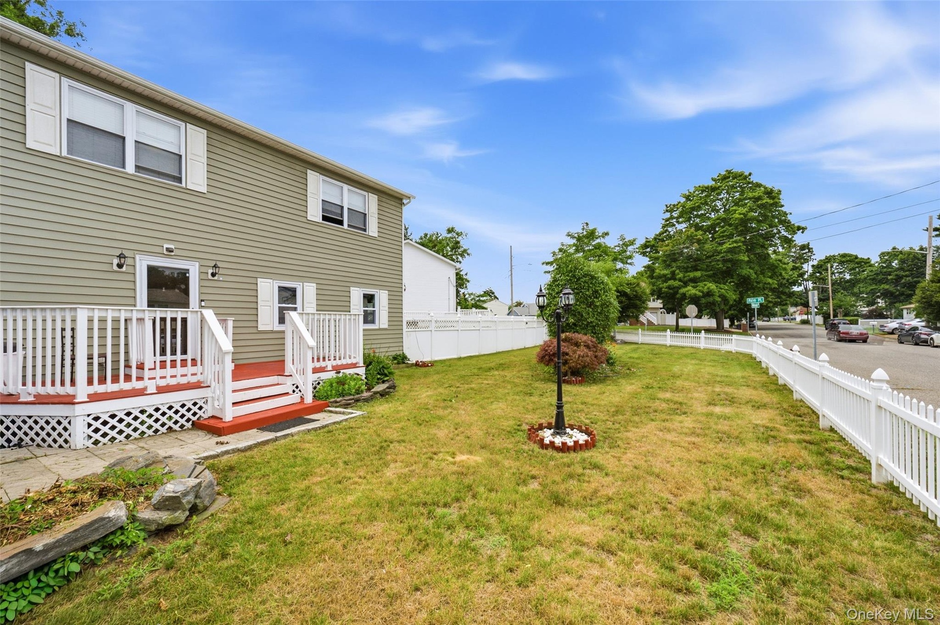 Front porch and nicely landscaped yard with a white picket fence