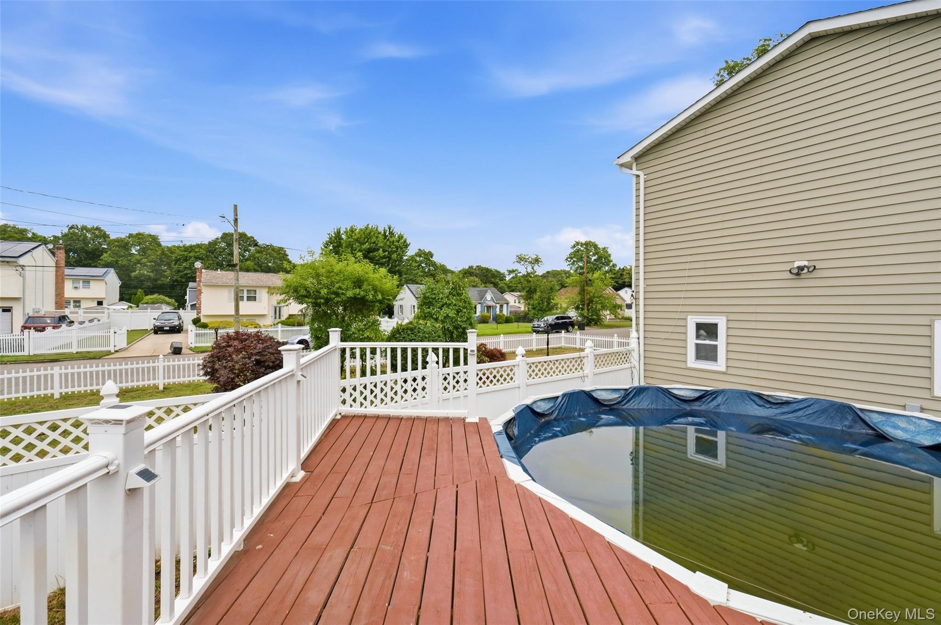 Expansive wood deck with white lattice and railing, overlooking an above-ground pool