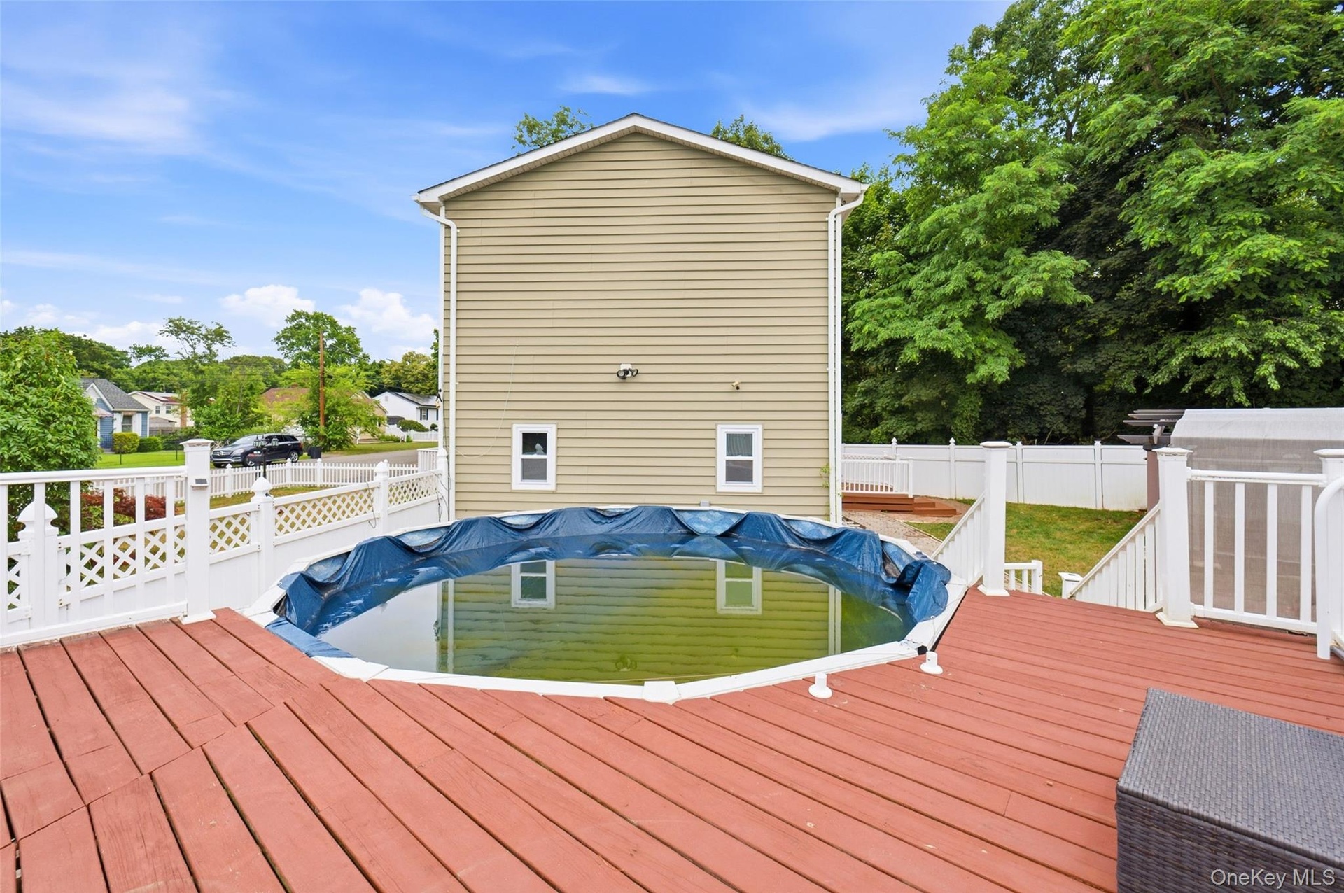 Staycation all summer long. Expansive rear deck featuring an above-ground pool and white lattice fencing