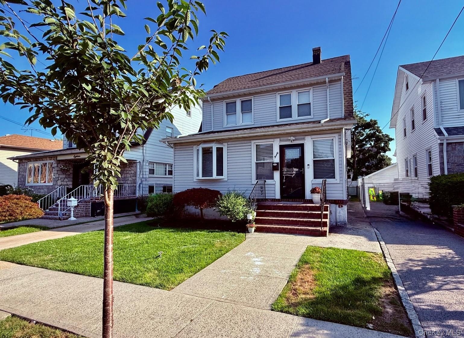 Two-story residence with light-colored siding, dark shingle roof, and a paved driveway