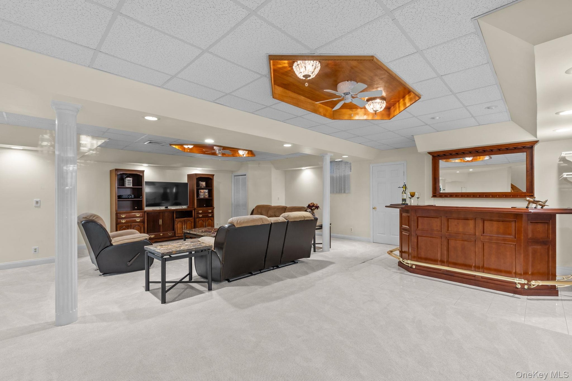 Large and versatile recreation space with a dedicated bar, recessed lighting, and carpeting—ideal for movie nights, game days, and gatherings.