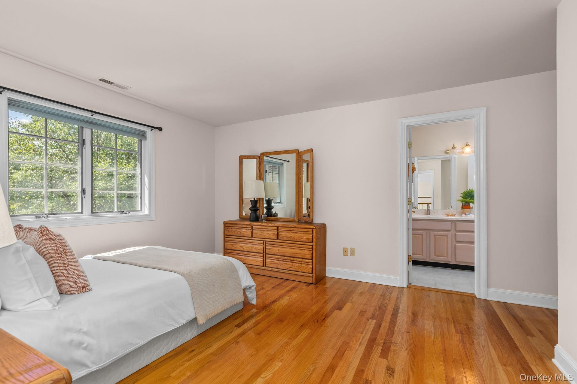 Bright and inviting bedroom with peaceful backyard views, hardwood floors, and convenient access to a shared bath.