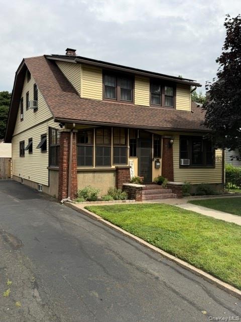 Two-story residence featuring light yellow siding and a brown shingle roof