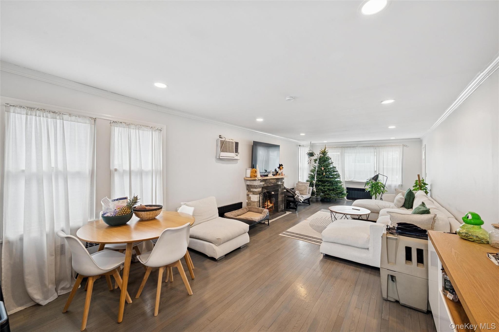 Living area with ornamental molding, dark wood-style floors, a stone fireplace, recessed lighting, and a wall mounted AC