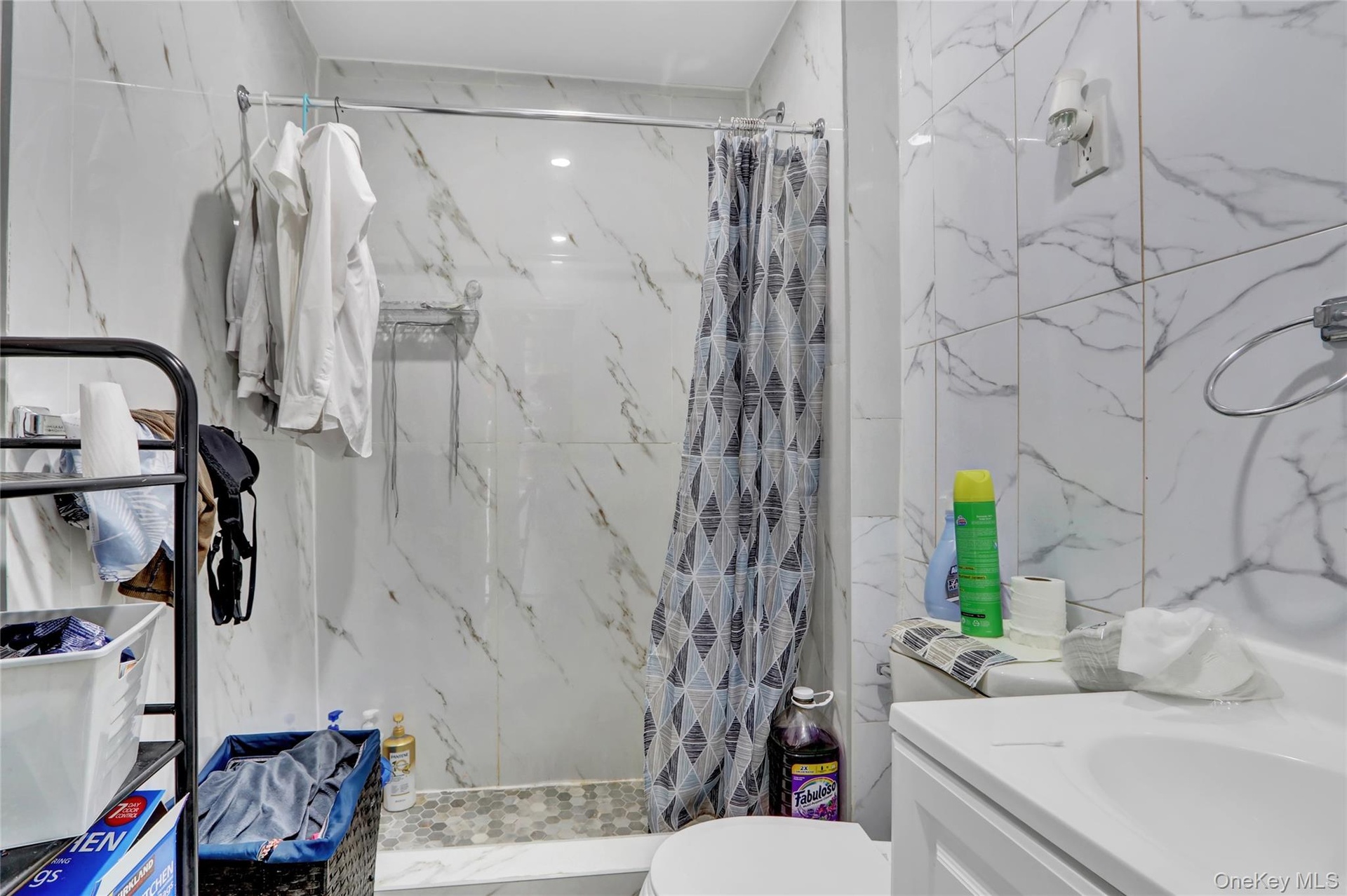 Bathroom featuring a walk-in shower with mosaic tile flooring, white marble-look wall tiling, and recessed lighting