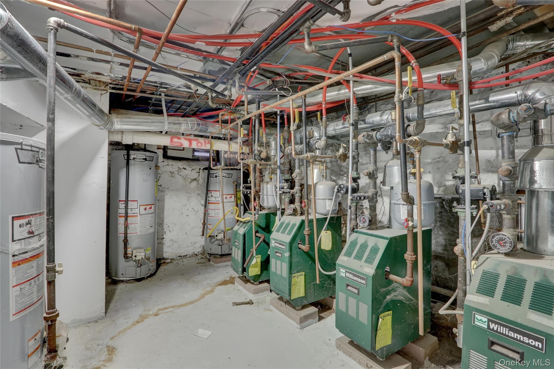 Utility room featuring multiple water heaters and boiler systems