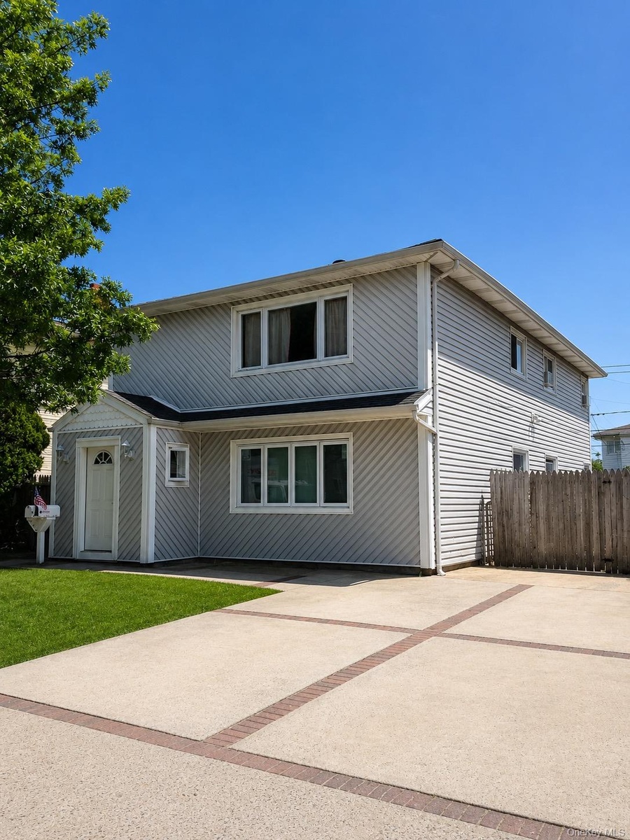 Two-story residence featuring light gray siding, white trim, and large private driveway.