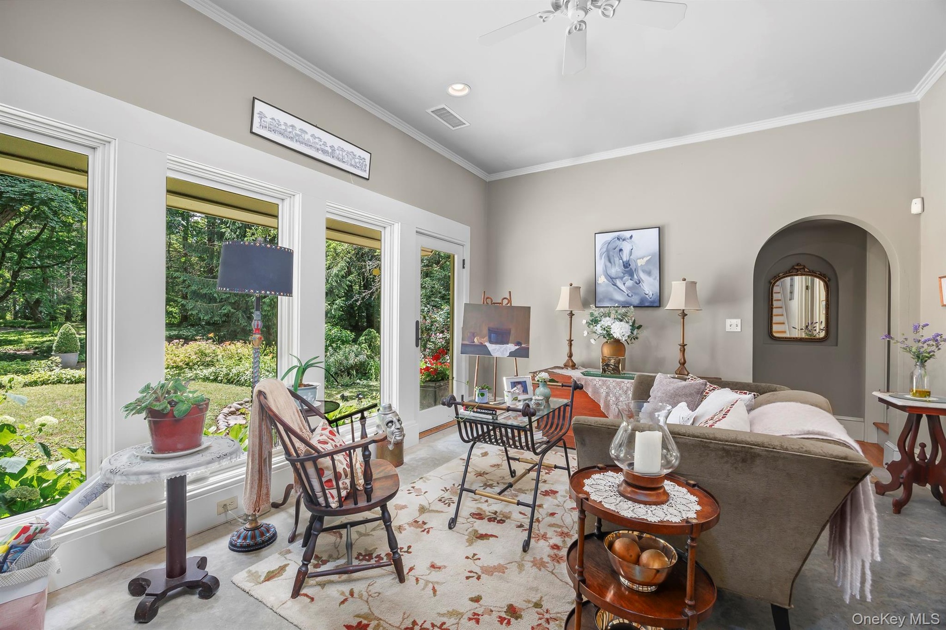 A wonderful sun room/den with a wall of windows overlooks lovely gardens