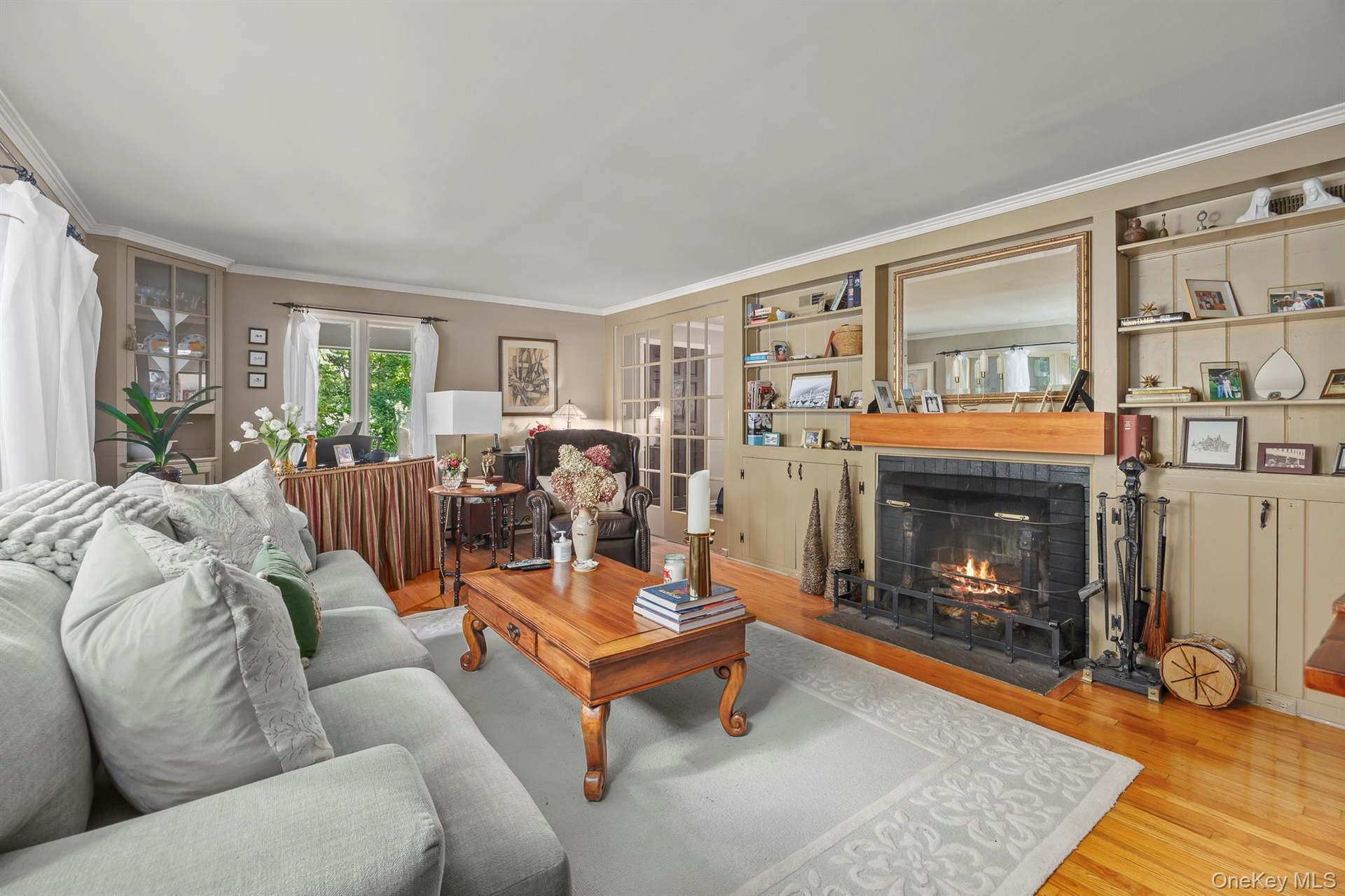The lovely living room with built-ins and fireplace is cozy and elegant