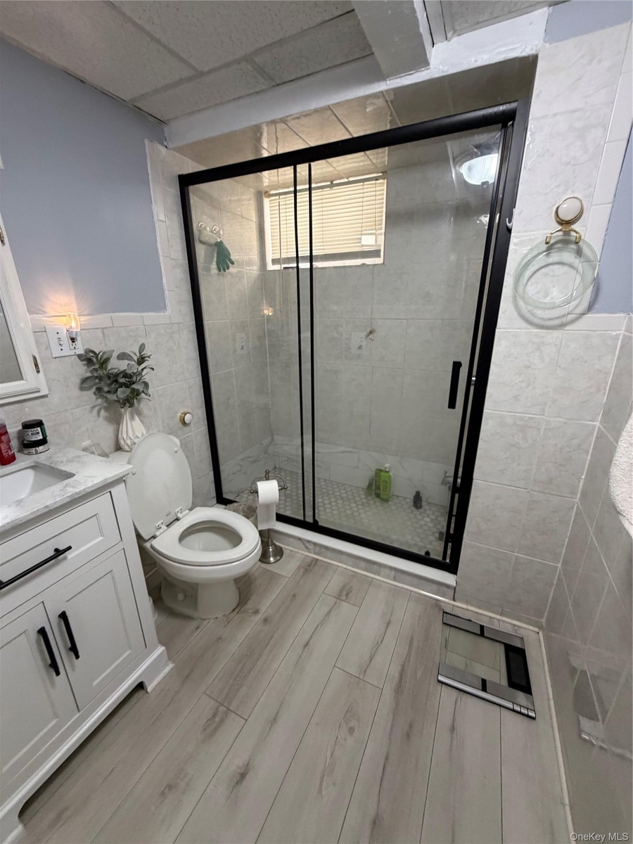 Contemporary bathroom featuring a glass-enclosed shower with a black frame and tiled walls