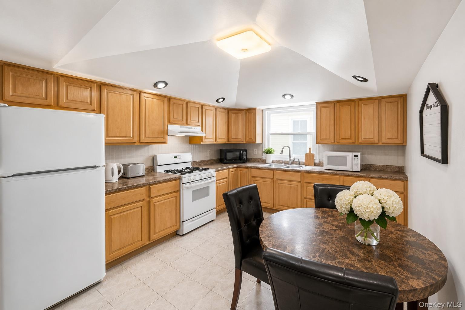 Kitchen featuring abundant wood cabinetry, white appliances, recessed lighting, and a window above the sink