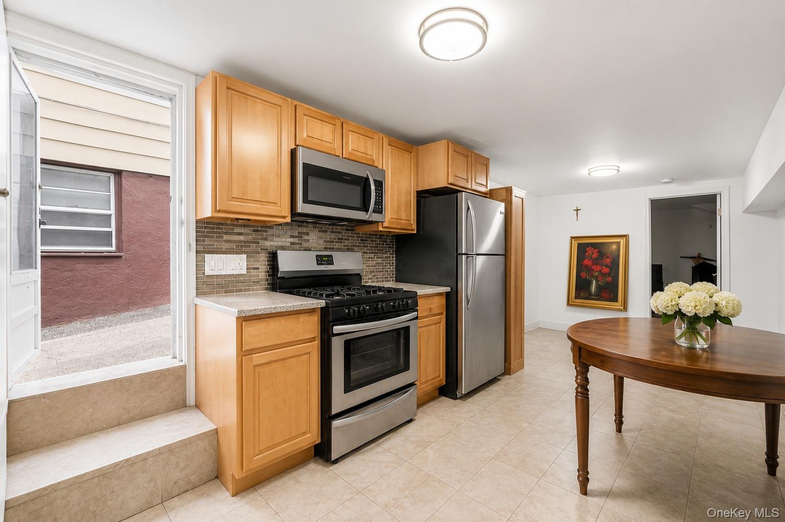 Compact kitchen featuring light wood cabinetry and stainless steel appliances