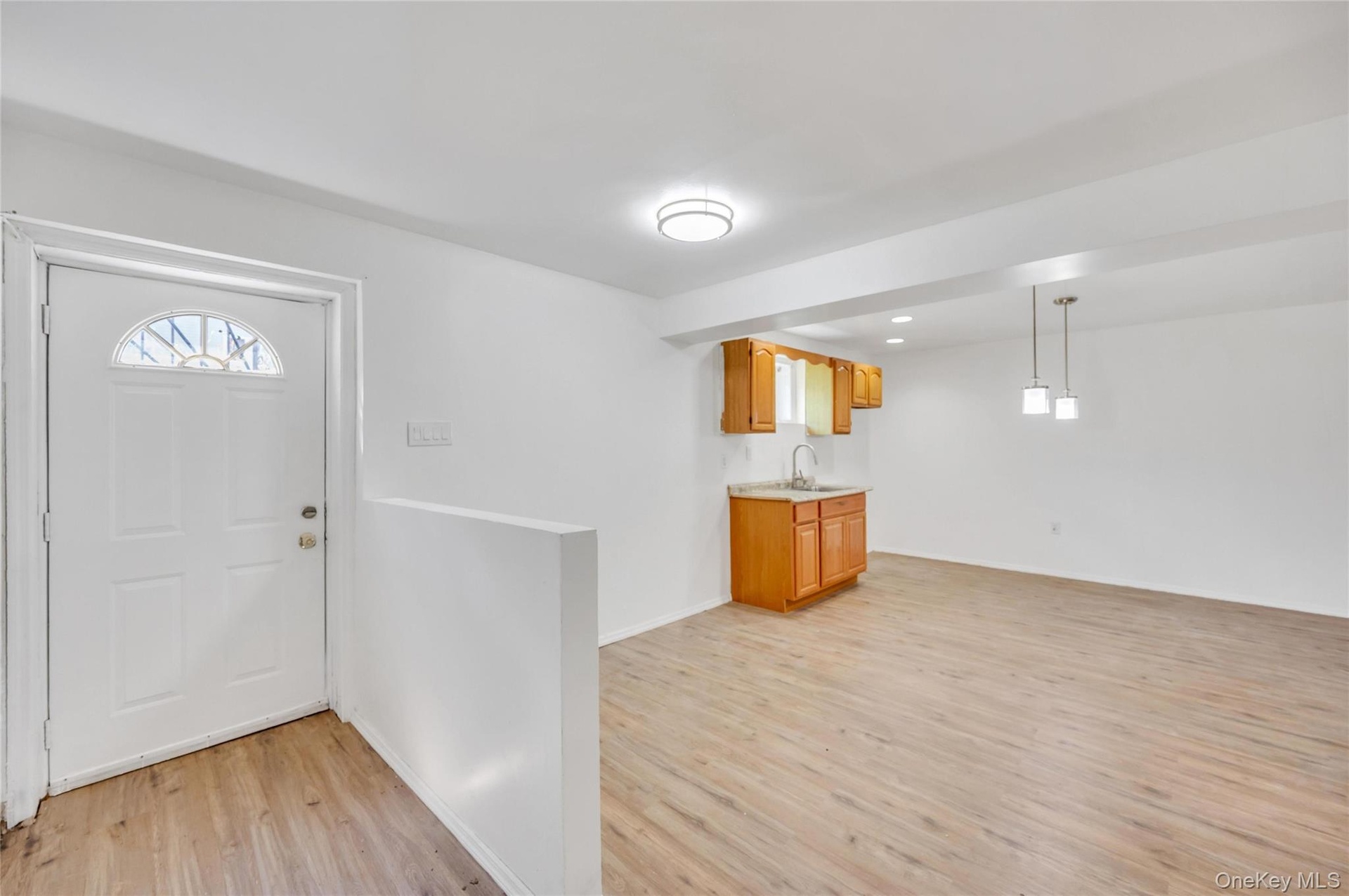 Entryway featuring a white paneled door with an arched transom window, wood-finish flooring, and a half-wall partition
