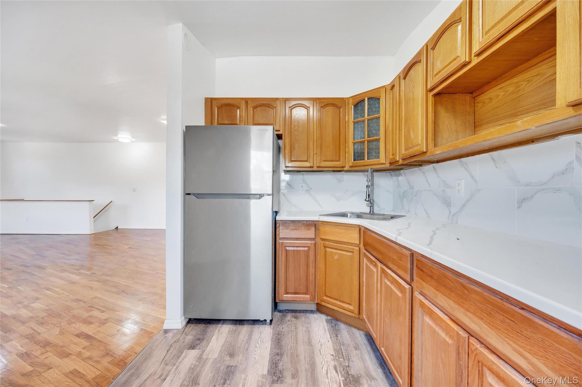 Kitchen area with natural wood cabinetry and a stainless steel refrigerator