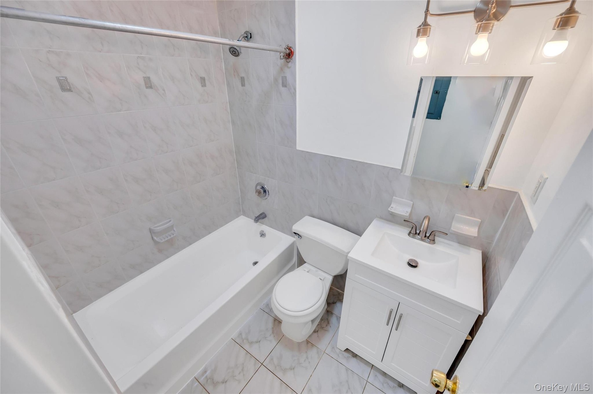 Bathroom featuring a white vanity with integrated sink, brushed nickel faucet, and a wall-mounted mirror