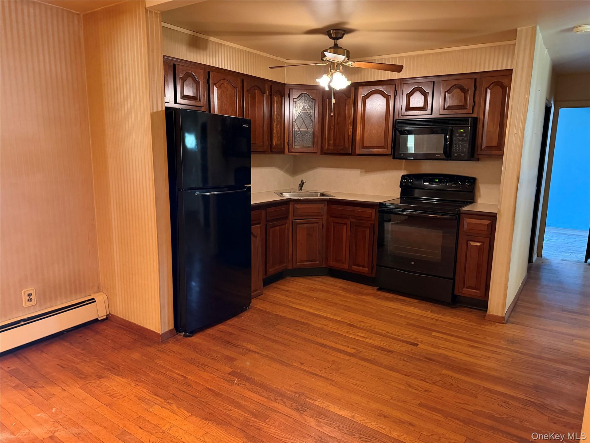 Kitchen featuring wood-finish flooring, dark wood cabinetry, and a ceiling fan