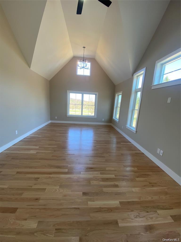 The primary suite serves as a private retreat, featuring a vaulted ceiling, beautifully finished red oak hardwood floors, and large windows that welco