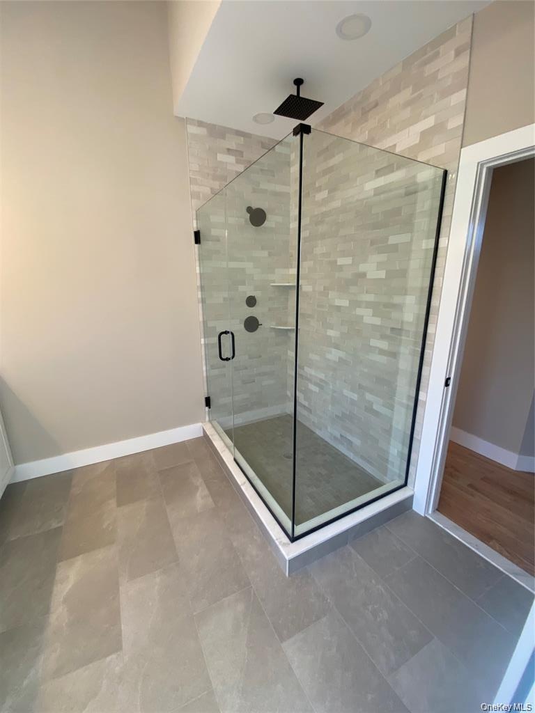 Floor-to-ceiling tile and a sleek glass enclosure transform the walk-in shower into a luxurious spa-like retreat.