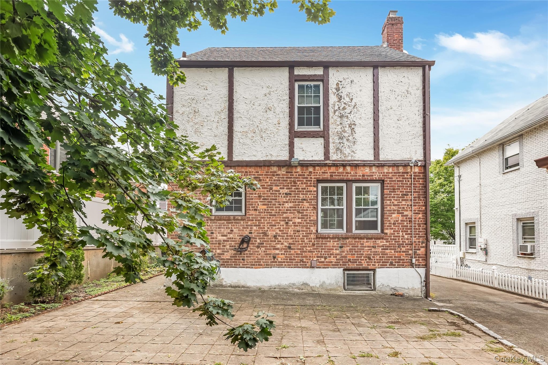 Brick and stucco exterior featuring multiple windows and a chimney
