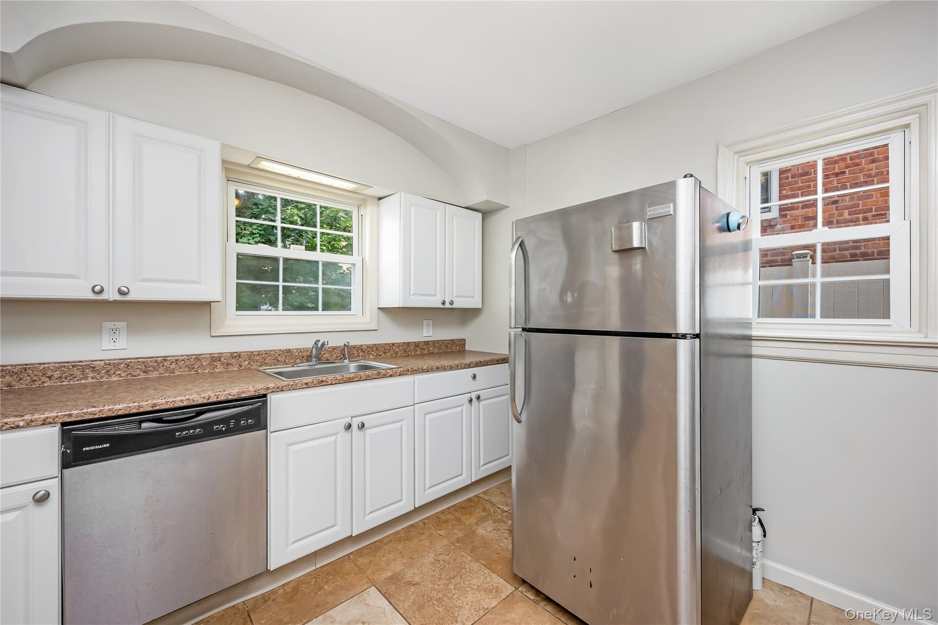Kitchen featuring white cabinetry, a stainless steel refrigerator, and stainless steel dishwasher
