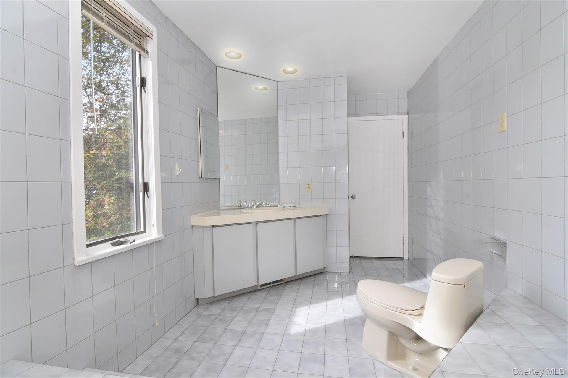 Primary full bath featuring tile walls, light tile patterned floors, recessed lighting, and vanity