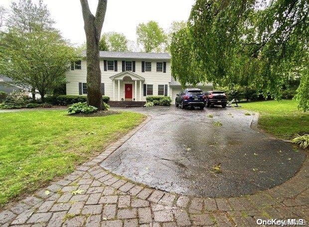 Colonial inspired home featuring asphalt driveway and a front yard